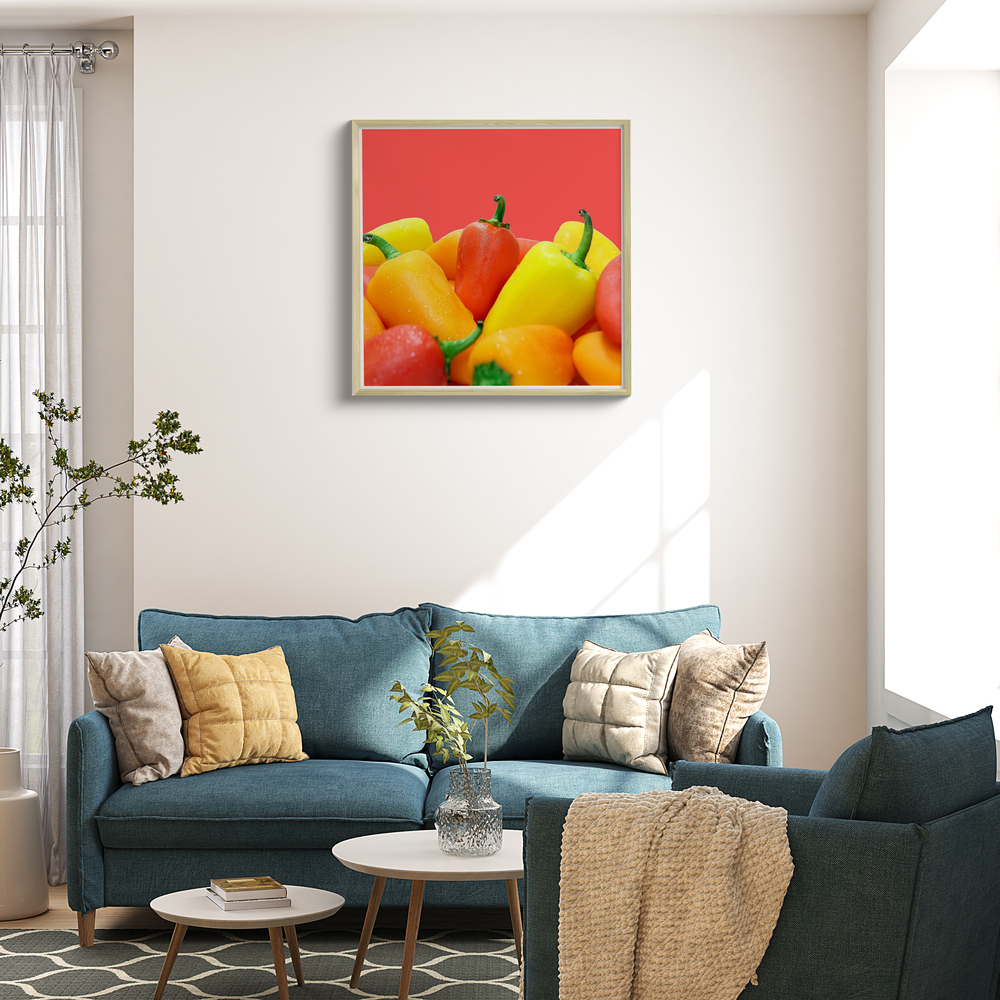 Fotoleinwand mit bunten Paprikas im hellen Holzrahmen über einem blauen Sofa im Wohnzimmer