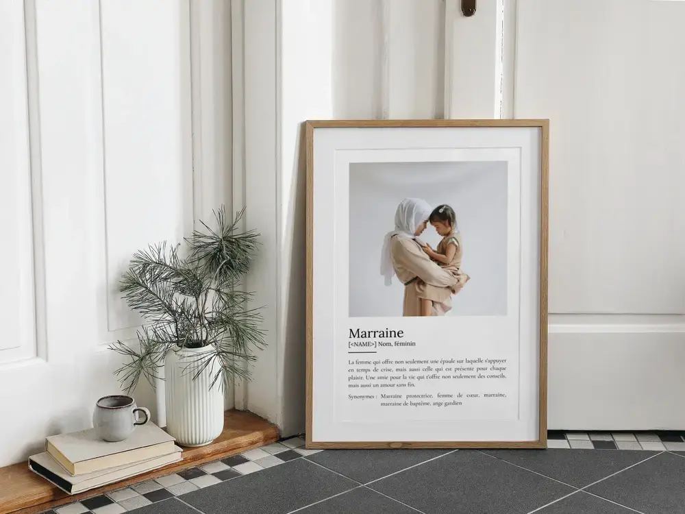 Affiche définition pour marraine avec photo, encadrée en bois clair et posée au sol près d’une plante