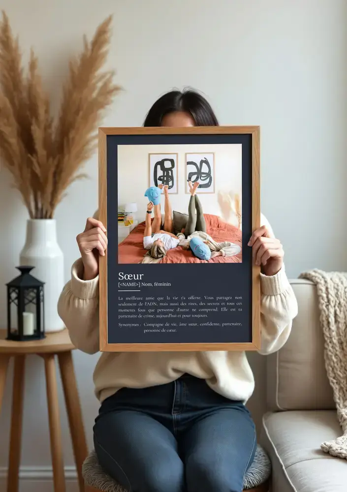 Idée cadeau pour sa sœur : affiche définition avec photo sur fond sombre, dans un cadre en bois près du canapé.