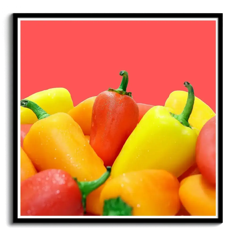 Fotoleinwand mit gelben, orangefarbenen und roten Paprikas vor rotem Hintergrund im schwarzen Rahmen