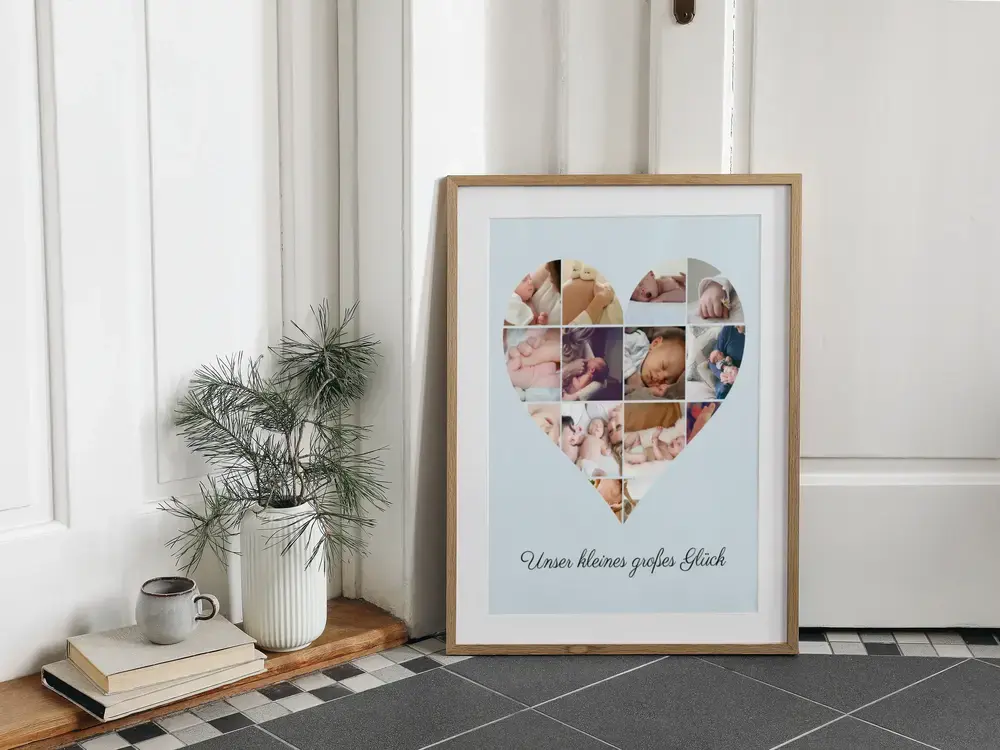 Babyfoto-Collage in Herzform mit Spruch im Naturholzrahmen, auf dem Fliesenboden neben einer Vase an die Wand gelehnt