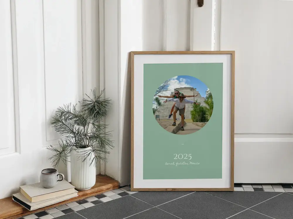 Affiche de voyage encadrée, photo ovale sur fond vert sauge, posée au sol : un cadeau souvenir de vacances