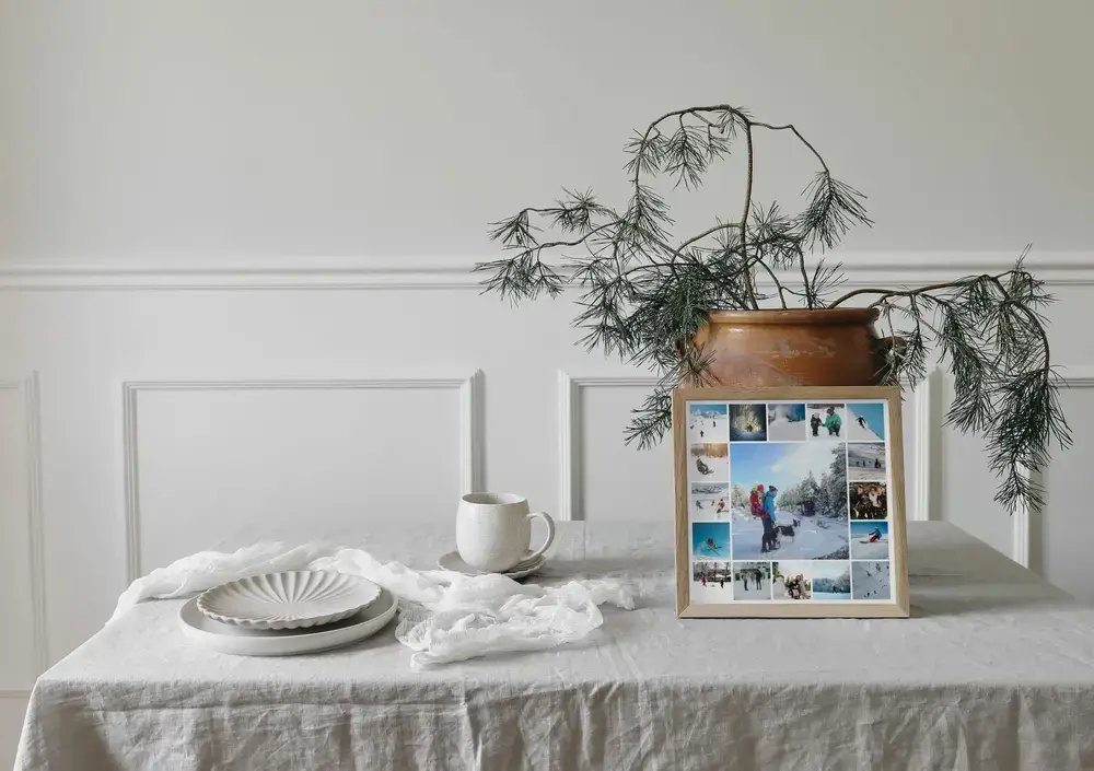 Collage photo d’hiver encadré, posé sur une table près de branches de sapin, une idée cadeau pour la famille