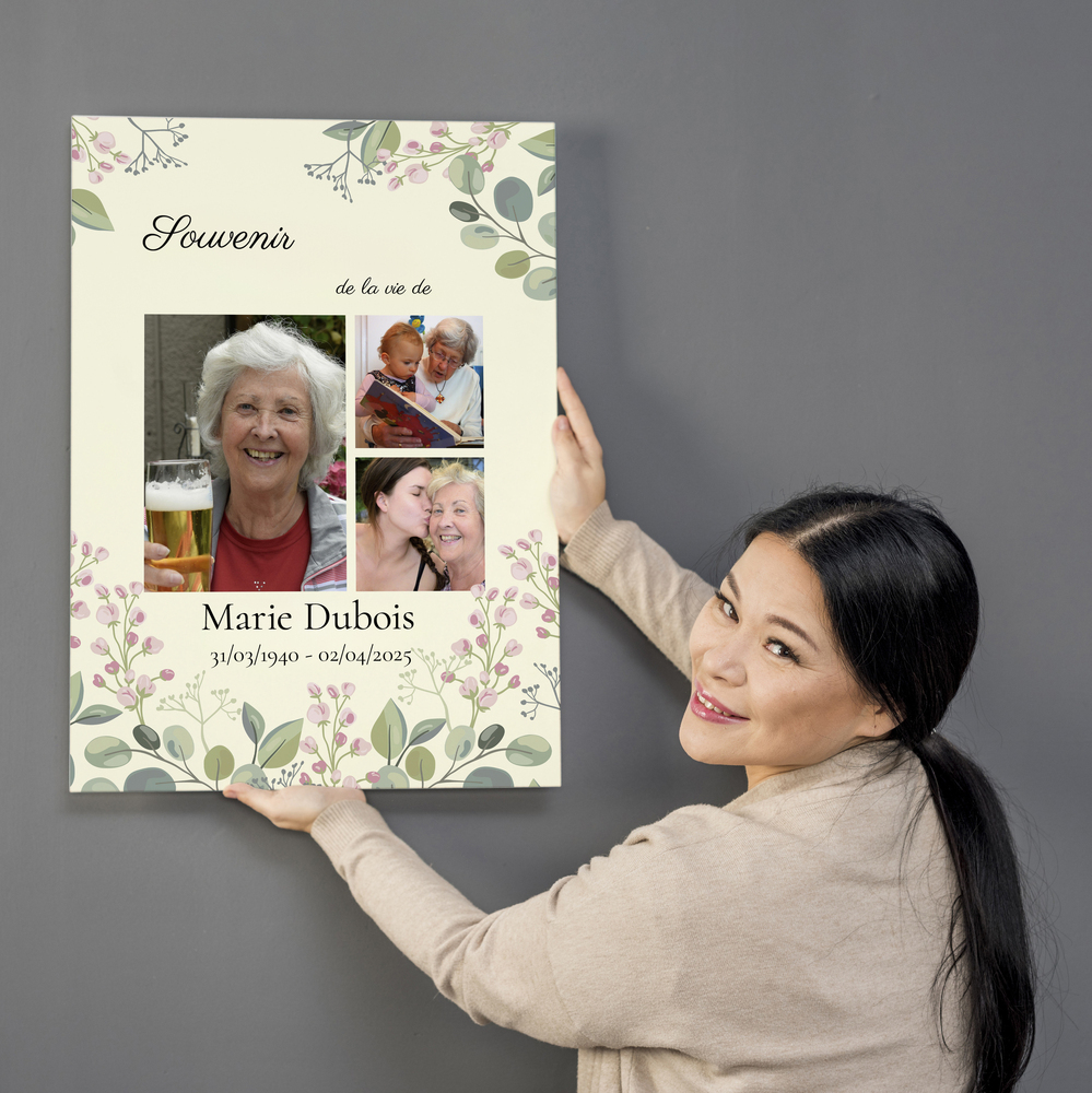 Toile commémorative avec trois photos, un décor floral et un nom personnalisé, présentée contre un mur gris