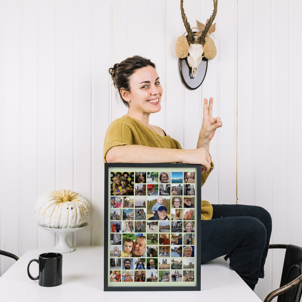 Schwarz gerahmte Familiencollage mit hervorgehobenen Kinderfotos auf einem weißen Tisch, als Geschenkidee für Großeltern