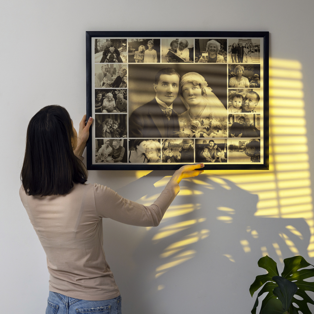 Trauercollage in Sepia im schwarzen Rahmen mit großem Hochzeitsporträt an einer Wand mit Sonnenstreifen